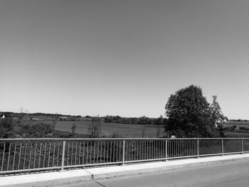 Road by trees against clear sky