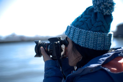 Woman photographing through camera against lake