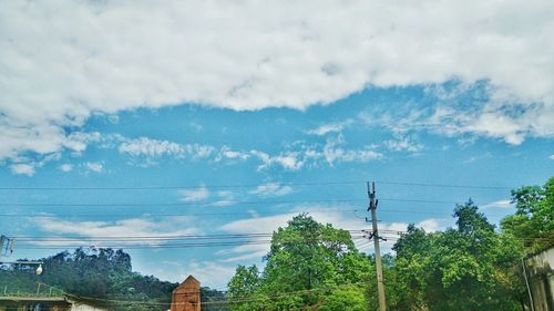 Low angle view of electricity pylon against cloudy sky