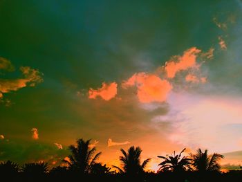 Low angle view of silhouette trees against dramatic sky