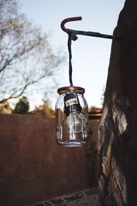 Light bulb in jar hanging against sky