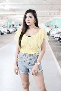 Beautiful young woman looking away while standing in parking lot