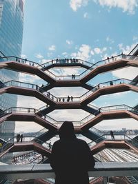 Low angle view of man standing on modern building against sky