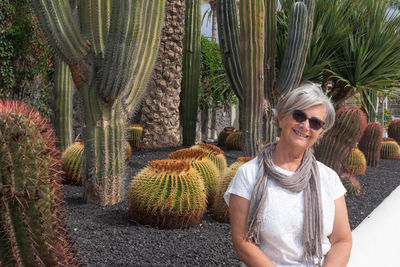 Portrait of smiling senior woman sitting against cactus