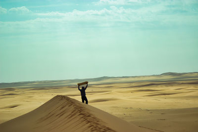 Rear view of man walking at beach against sky