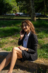 Young woman using laptop while sitting on field