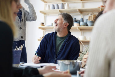 Smiling mature male student talking with female instructor in art studio