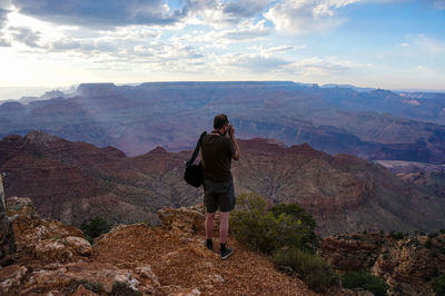 Rear view of man looking at the grand canyon against sky