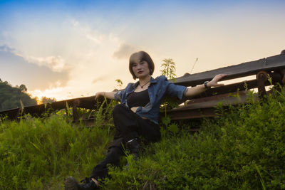 Portrait of young woman on field against sky during sunset