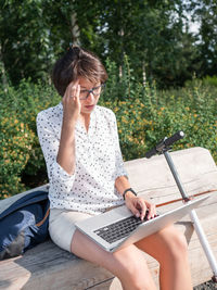 Young woman using laptop while sitting at park
