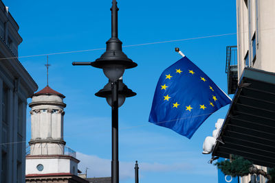 Low angle view of flags on buildings against blue sky