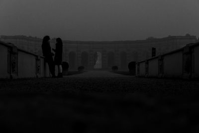 People walking on railing against sky during foggy weather