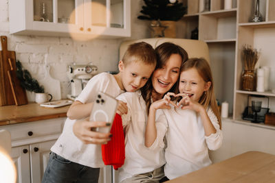 Mom with two children smile and take selfies using a mobile phone and technology on holiday