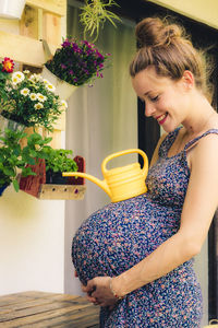 Side view of young woman holding potted plant