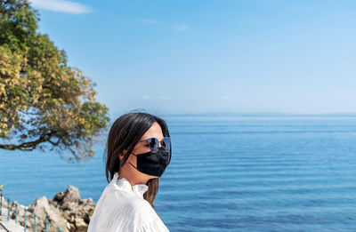 Young woman wearing black mask at beach. summer, tourism, virus, corona, covid-19