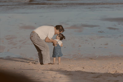 Full length of mother and daughter on beach