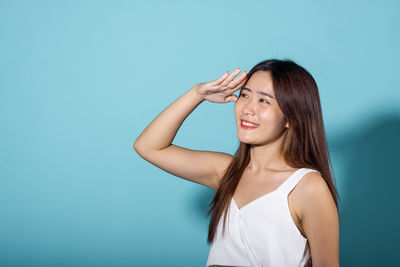 Young woman looking away against blue background