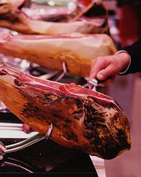 Cropped image of hand cutting jamon serrano