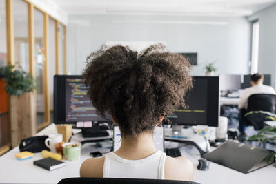 Female computer programmer with curly hair sitting at desk in office