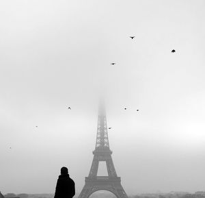 Side view of man looking at eiffel tower during foggy weather