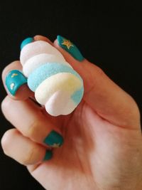 Close-up of hand holding ice cream cone against black background