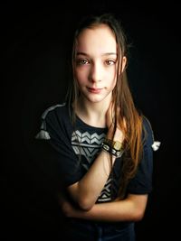 Portrait of beautiful young woman against black background