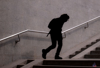 Silhouette man walking on staircase against wall