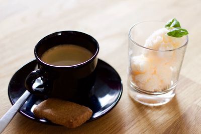Coffee cup with cookie and sorbet in glass garnished with mint leaves