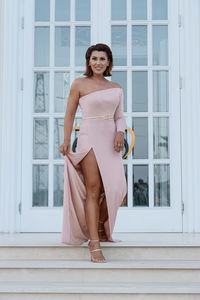 Portrait of a smiling young woman standing against window