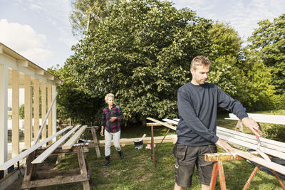 Man with female farm worker making shed against trees