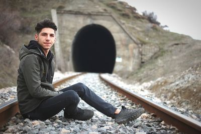 Portrait of young man sitting on rock