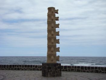 Wooden jetty on calm sea against cloudy sky