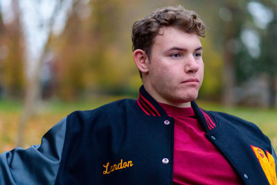 Young man looking away while sitting outdoors