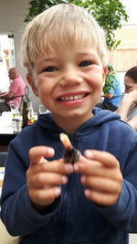 Portrait of smiling boy holding food in restaurant