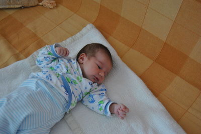 Close-up of cute baby lying on bed at home