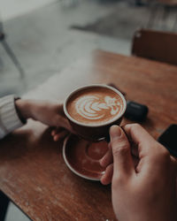 Midsection of woman holding coffee cup on table