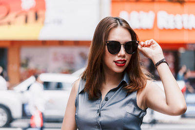 Close-up of smiling young woman wearing sunglasses in city 