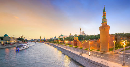 River amidst buildings against sky at sunset