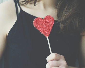 Midsection of woman holding heart shape candy