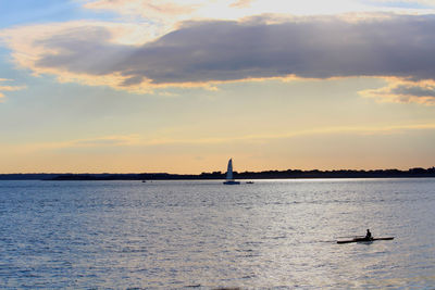 Silhouette sailboat in sea against sky during sunset