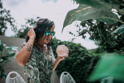 Midsection of woman with sunglasses against plants