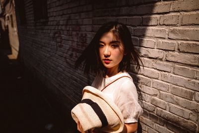 Portrait of young woman sitting against wall