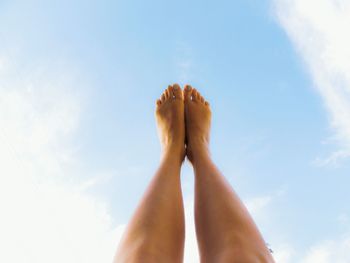 Low section of woman with feet up against sky