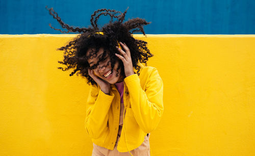 Portrait of woman standing against yellow wall