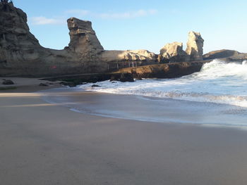 Rock formations on beach against sky