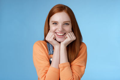 Portrait of a smiling young woman against blue background