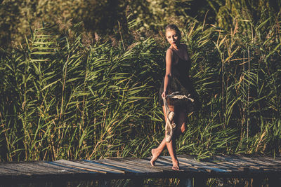 Portrait of young woman standing against plants