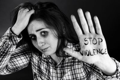 Portrait of woman with hand in hair showing stop violence text on palm