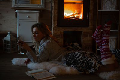 Beautiful woman holding wine glass in cozy mountain cabin