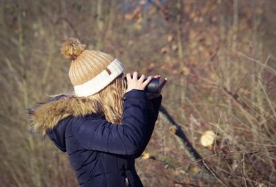 Rear view of woman wearing hat standing on field